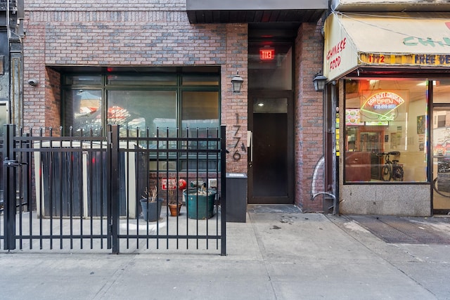 view of exterior entry with brick siding and fence