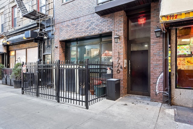 entrance to property with brick siding and fence