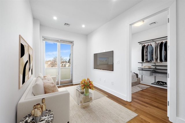 living room featuring recessed lighting, visible vents, baseboards, and wood finished floors