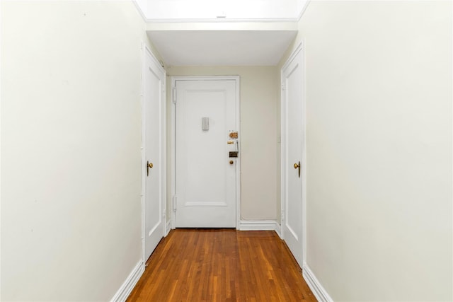 corridor with baseboards and wood finished floors