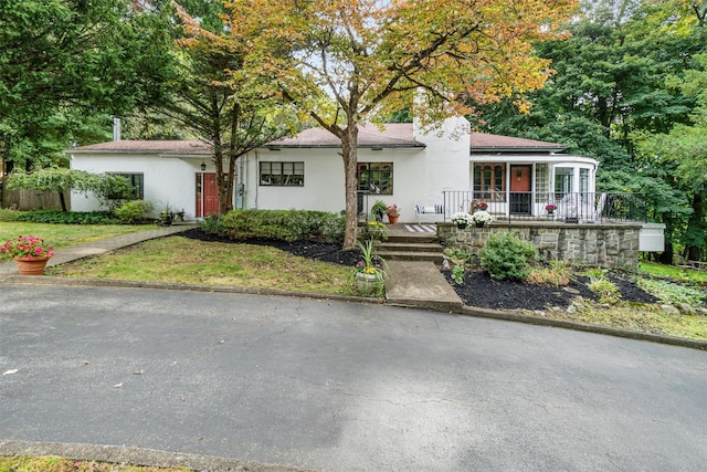 ranch-style home with a front yard, covered porch, and stucco siding