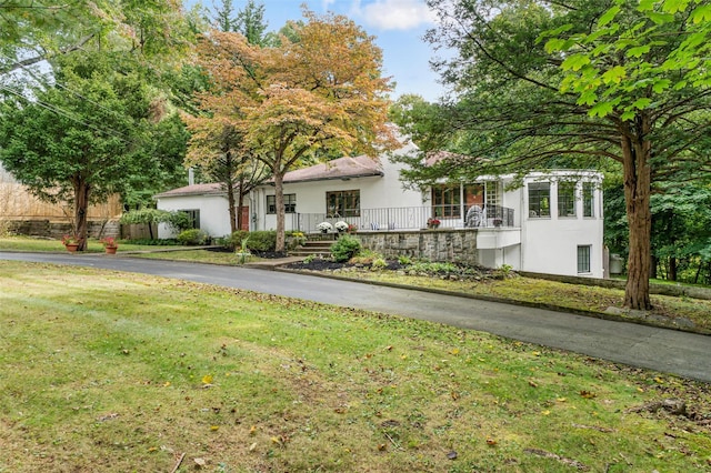 view of front of property with aphalt driveway, stucco siding, and a front lawn