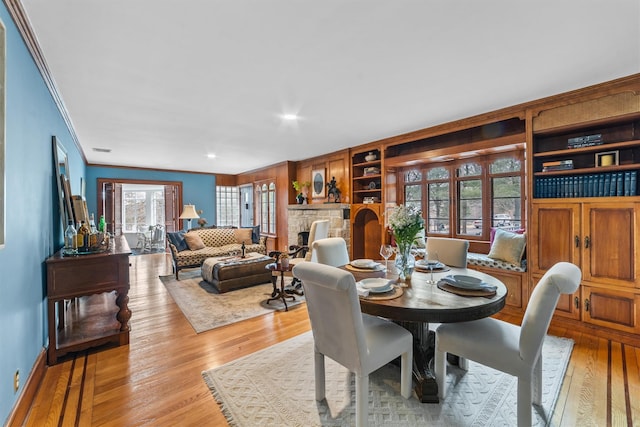 dining space featuring a fireplace, crown molding, and hardwood / wood-style floors