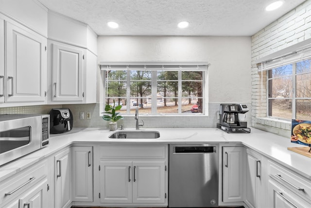 kitchen featuring a sink, white cabinetry, stainless steel appliances, light countertops, and decorative backsplash