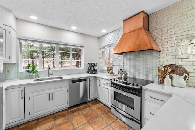 kitchen featuring custom exhaust hood, white cabinets, stainless steel appliances, and a sink