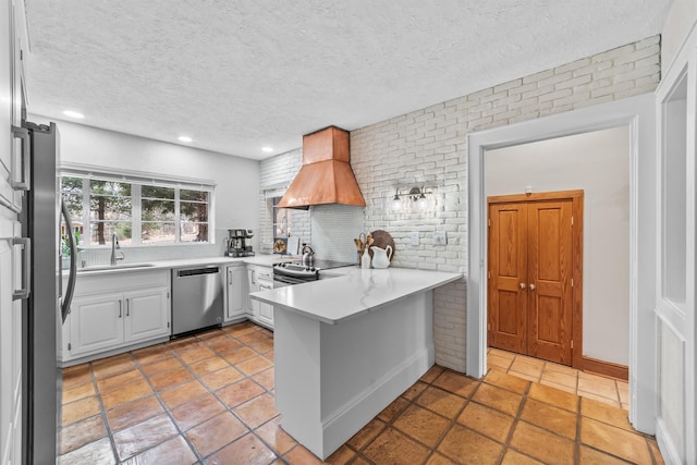 kitchen featuring a sink, stainless steel appliances, a peninsula, light countertops, and custom exhaust hood