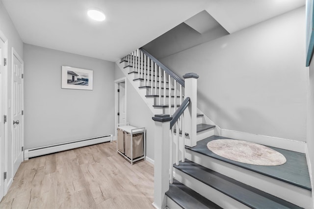 stairs with wood finished floors and a baseboard radiator