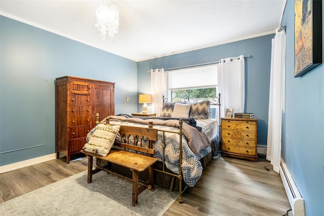 bedroom with wood finished floors, baseboards, a baseboard radiator, ornamental molding, and baseboard heating