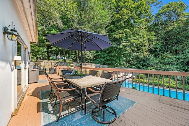 deck with a fenced in pool, outdoor dining area, and fence