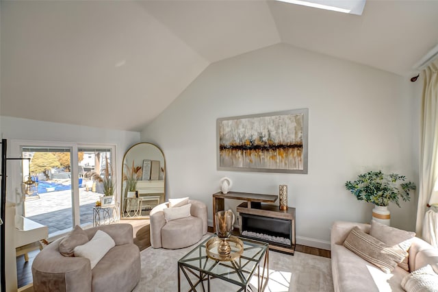 living room featuring vaulted ceiling, light wood finished floors, a fireplace, and baseboards