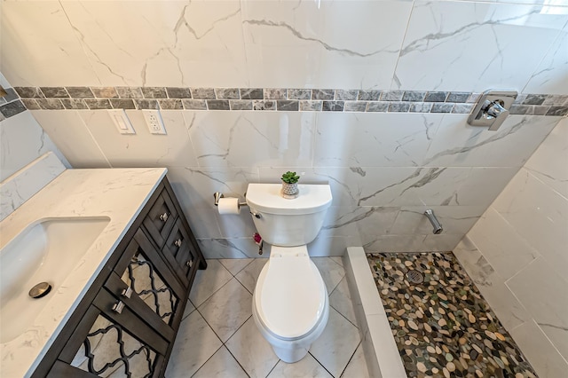 bathroom with tile walls, toilet, a stall shower, vanity, and tile patterned flooring