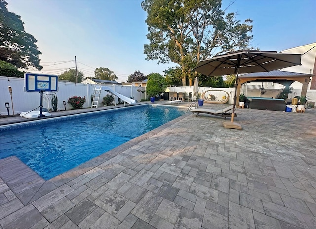 view of pool with a fenced backyard, a patio, a water slide, and a gazebo