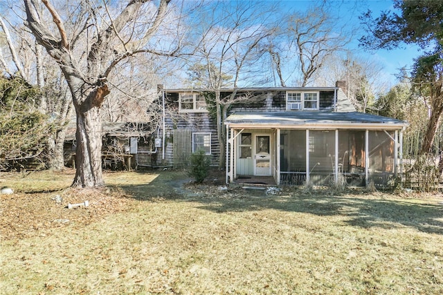 view of front of home featuring a front yard, a sunroom, and a chimney