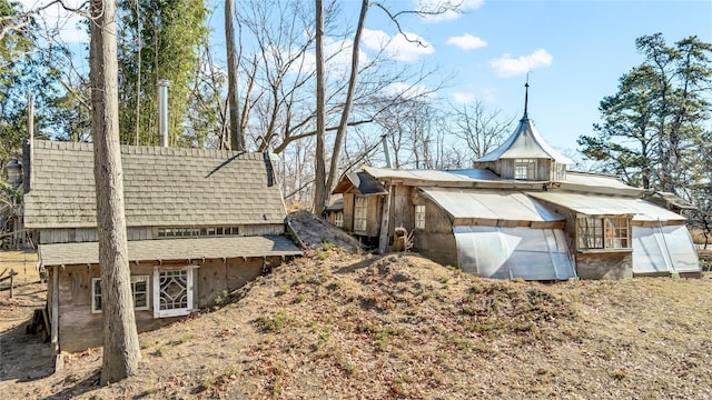 view of side of home featuring roof with shingles and an outbuilding