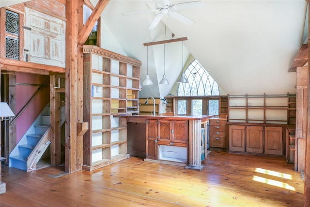 interior space with light wood-style floors, ceiling fan, high vaulted ceiling, and brown cabinets