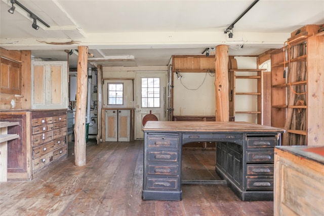 unfurnished office featuring track lighting, dark wood-type flooring, and a workshop area