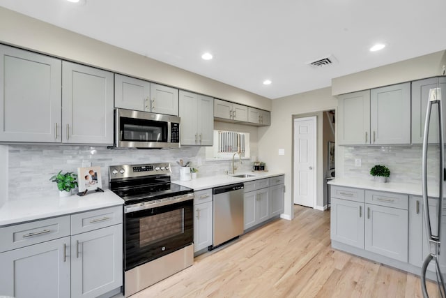 kitchen with light wood finished floors, visible vents, stainless steel appliances, and light countertops