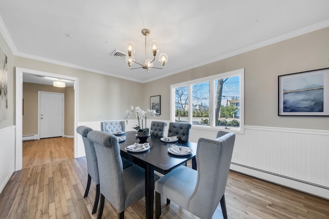 dining space with visible vents, wainscoting, a baseboard radiator, an inviting chandelier, and light wood-type flooring