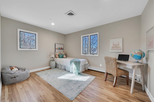 bedroom featuring light wood-style flooring, baseboard heating, visible vents, and baseboards