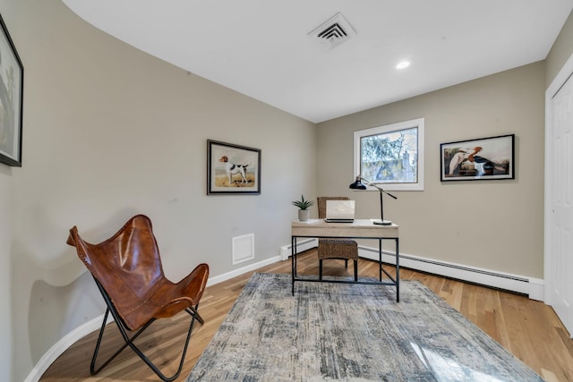 home office with light wood finished floors, a baseboard radiator, and visible vents