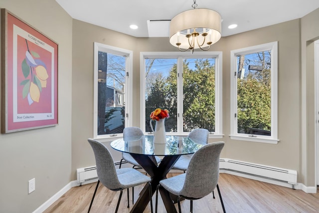 dining space featuring a wealth of natural light, a baseboard radiator, and light wood-style flooring