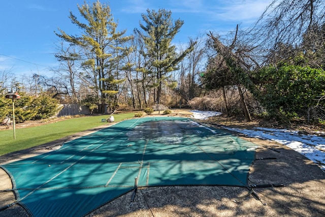 view of swimming pool with a covered pool, fence, and a yard