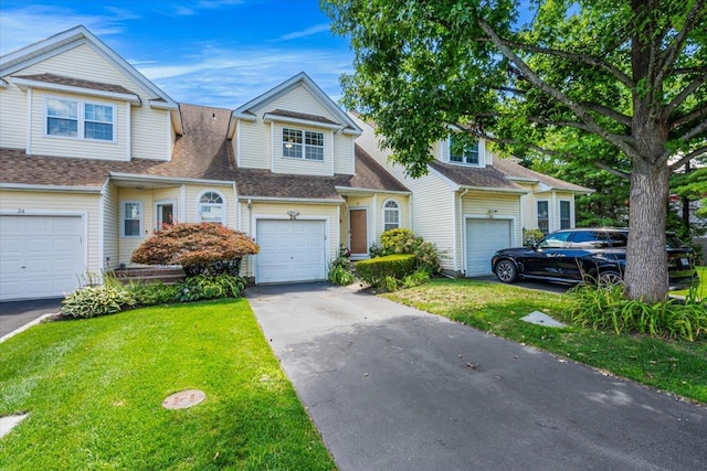 view of front of property with a garage, driveway, roof with shingles, and a front yard