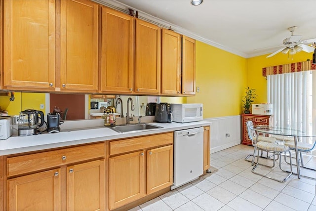 kitchen with white appliances, wainscoting, ceiling fan, light countertops, and a sink