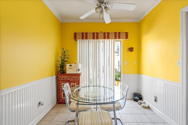 dining room featuring ceiling fan, ornamental molding, wainscoting, and light tile patterned flooring