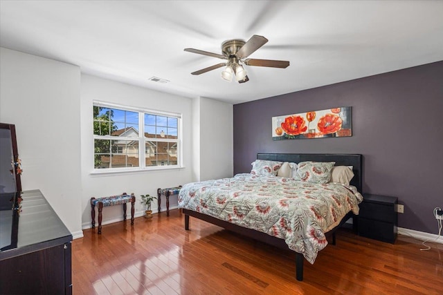 bedroom featuring a ceiling fan, hardwood / wood-style flooring, visible vents, and baseboards