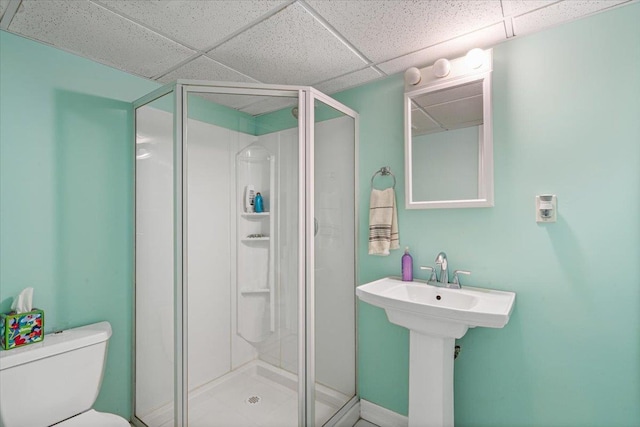 bathroom with toilet, a shower stall, and a drop ceiling