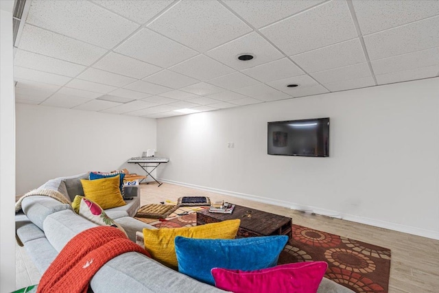 living area with a drop ceiling, wood finished floors, and baseboards