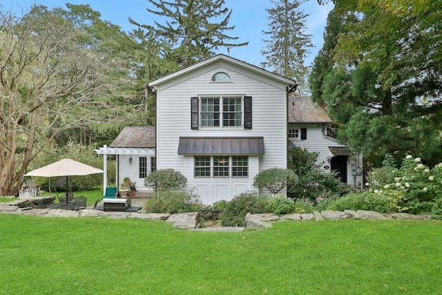 back of house featuring a standing seam roof, a yard, and metal roof