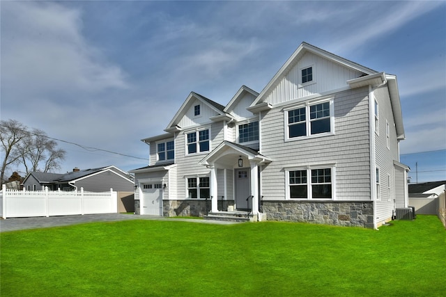 view of front facade featuring an attached garage, board and batten siding, central AC, fence, and a front lawn