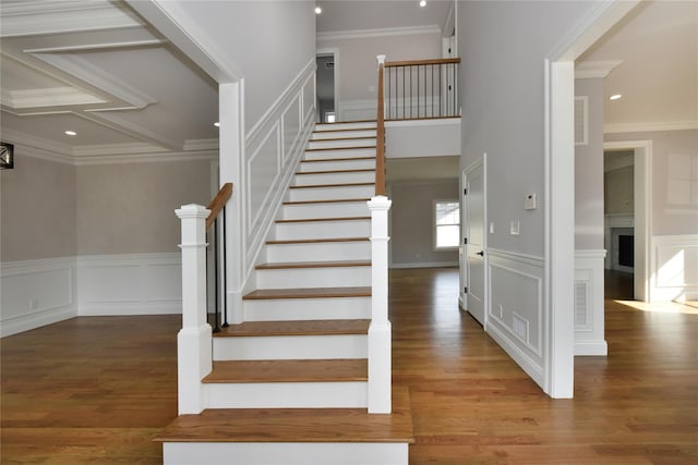 stairs with a fireplace, crown molding, visible vents, a decorative wall, and wood finished floors