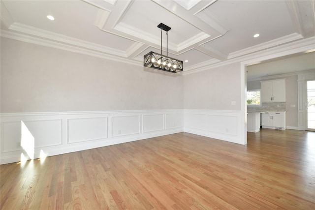 unfurnished dining area with light wood-style floors, a notable chandelier, and crown molding