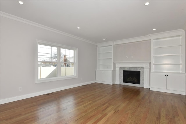 unfurnished living room with ornamental molding, wood finished floors, a high end fireplace, and baseboards