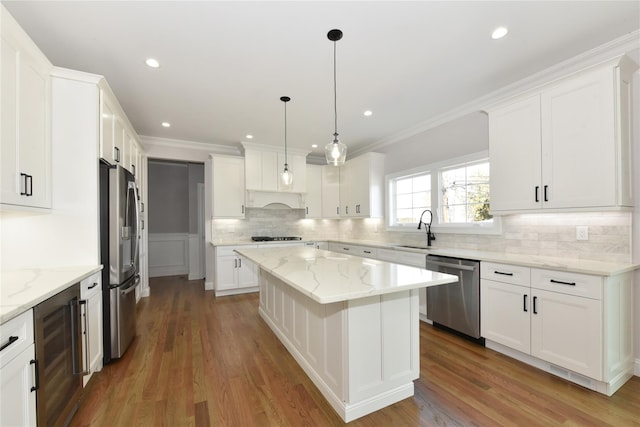 kitchen with a center island, pendant lighting, stainless steel appliances, a sink, and beverage cooler