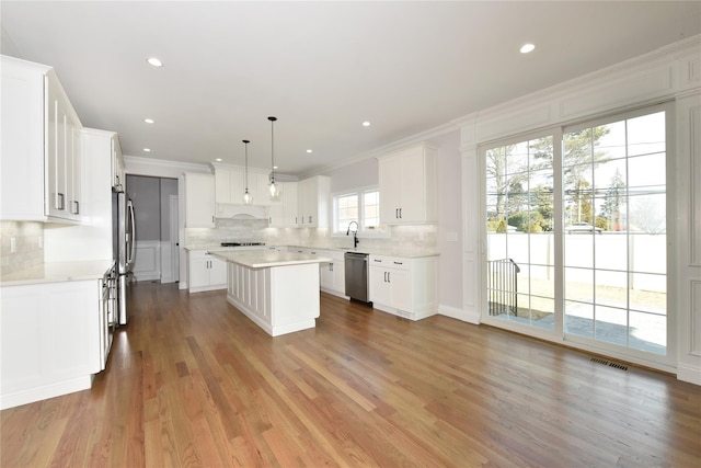 kitchen featuring white cabinetry, a kitchen island, appliances with stainless steel finishes, and light countertops