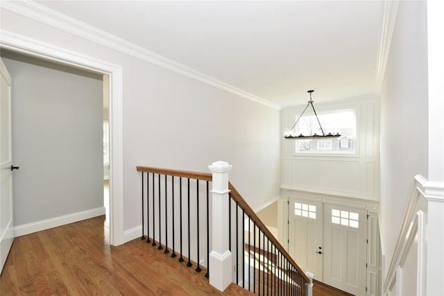 foyer entrance featuring a notable chandelier, crown molding, baseboards, and wood finished floors