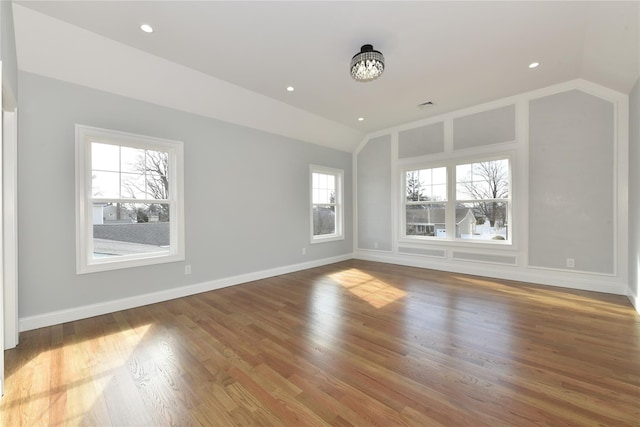 spare room with recessed lighting, vaulted ceiling, baseboards, and wood finished floors