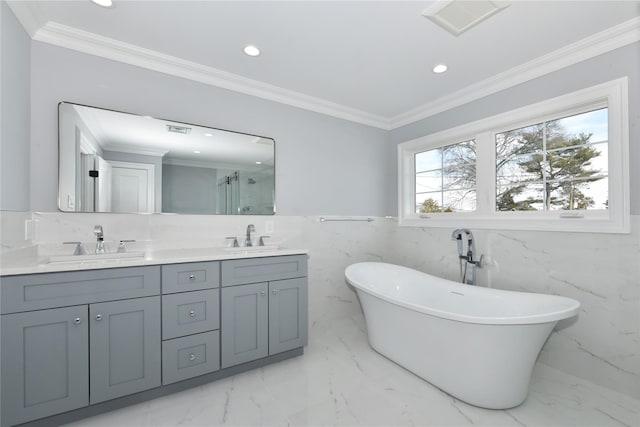 full bath with a freestanding bath, ornamental molding, and a sink