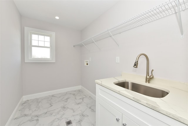 washroom featuring marble finish floor, hookup for a washing machine, baseboards, and a sink