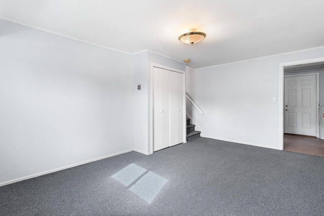 spare room with stairs, baseboards, dark colored carpet, and crown molding