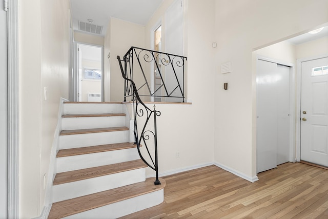 stairs with visible vents, baseboards, and wood finished floors