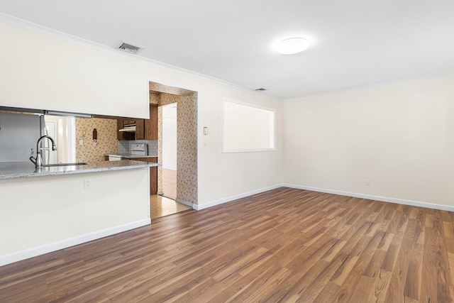 unfurnished living room with baseboards, visible vents, dark wood finished floors, ornamental molding, and a sink