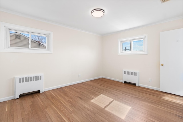 empty room with crown molding, radiator heating unit, light wood-style flooring, and baseboards