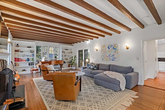 living area with beamed ceiling, a fireplace, and wood finished floors