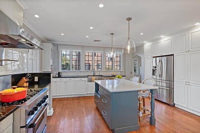 kitchen with appliances with stainless steel finishes, arched walkways, white cabinetry, and island exhaust hood