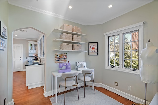 office space featuring light wood-style floors, visible vents, arched walkways, and crown molding